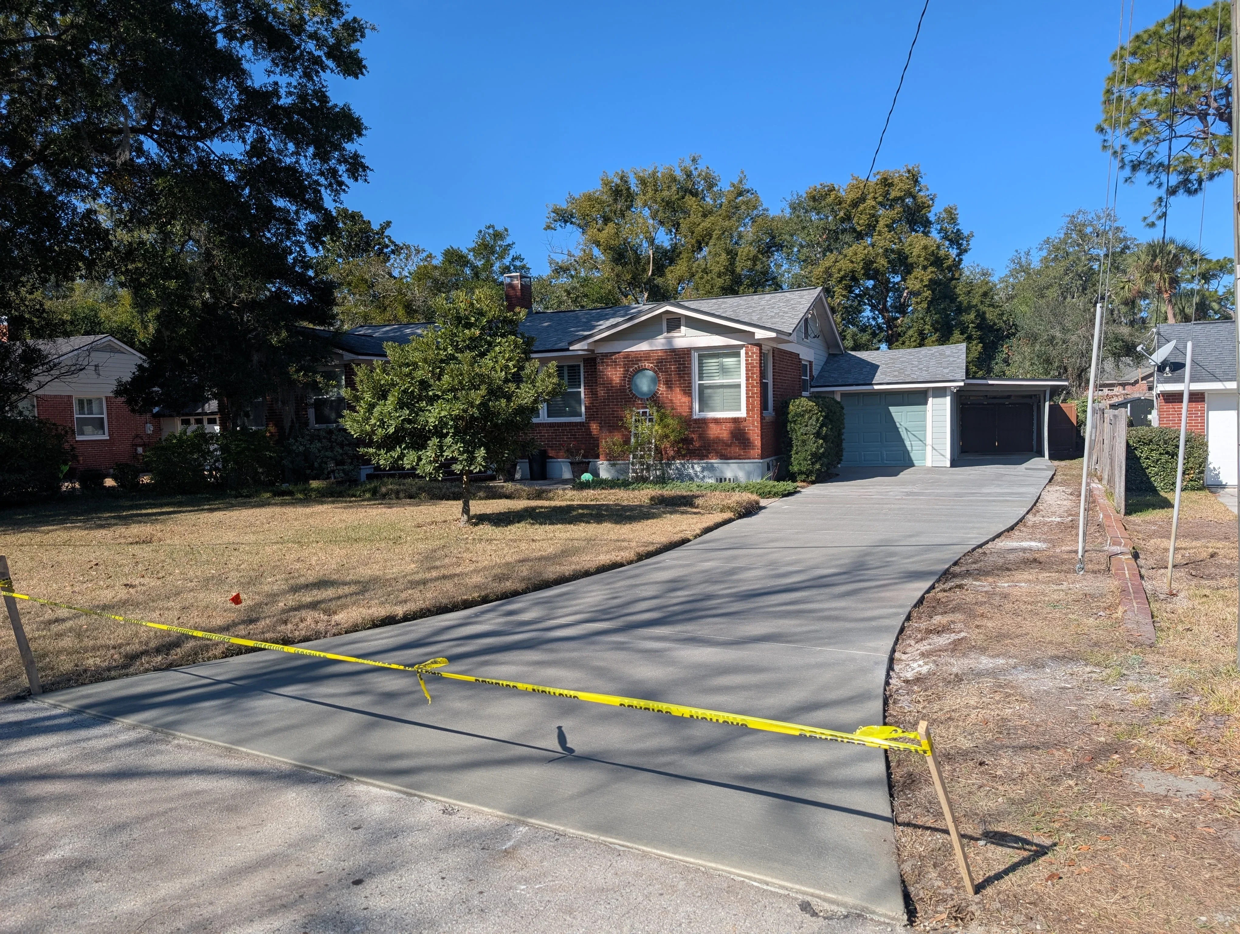 New concrete driveway with smooth finish leading to brick home garage