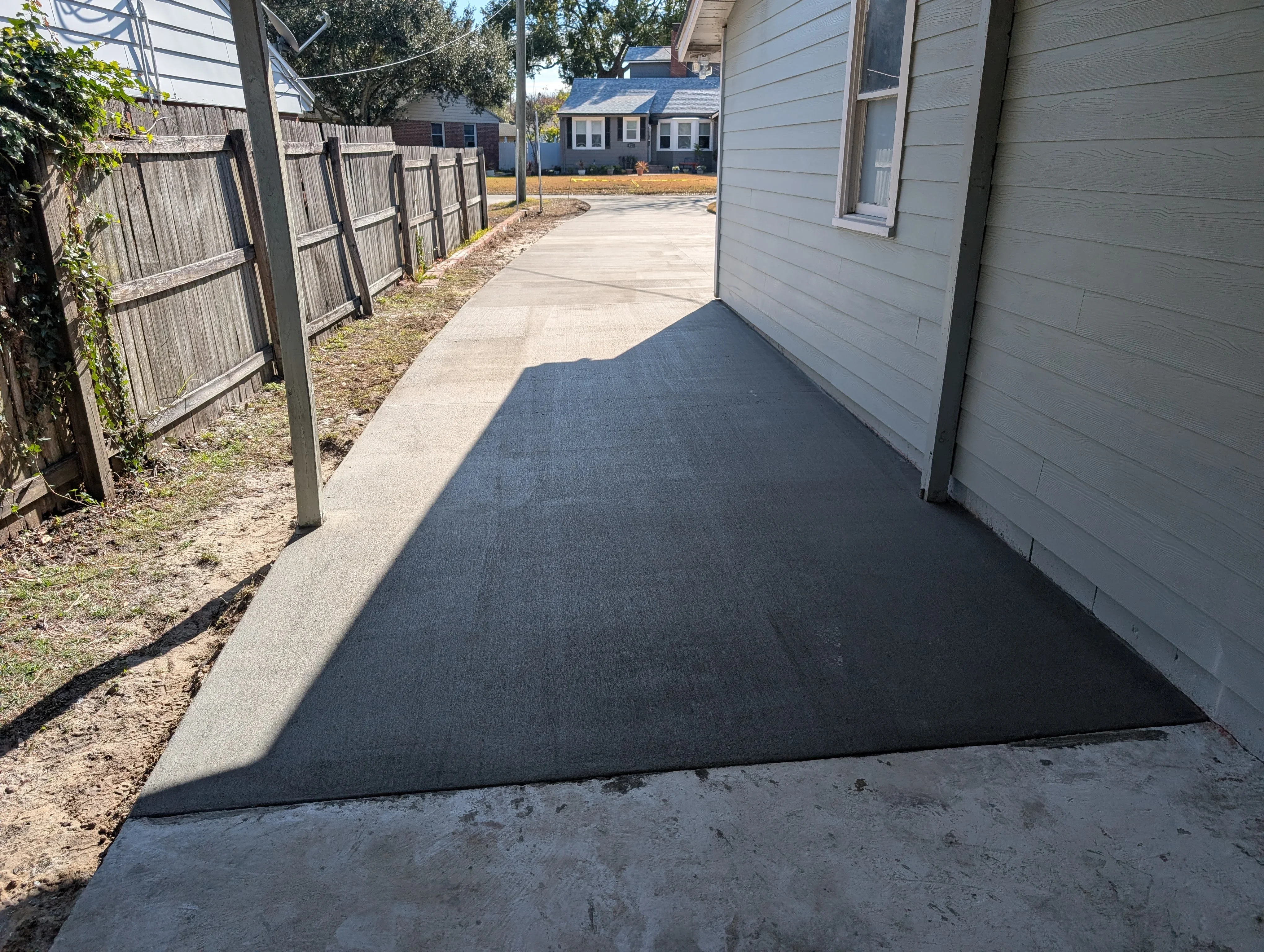 New concrete pad with finished surface and clean edges next to residential house
