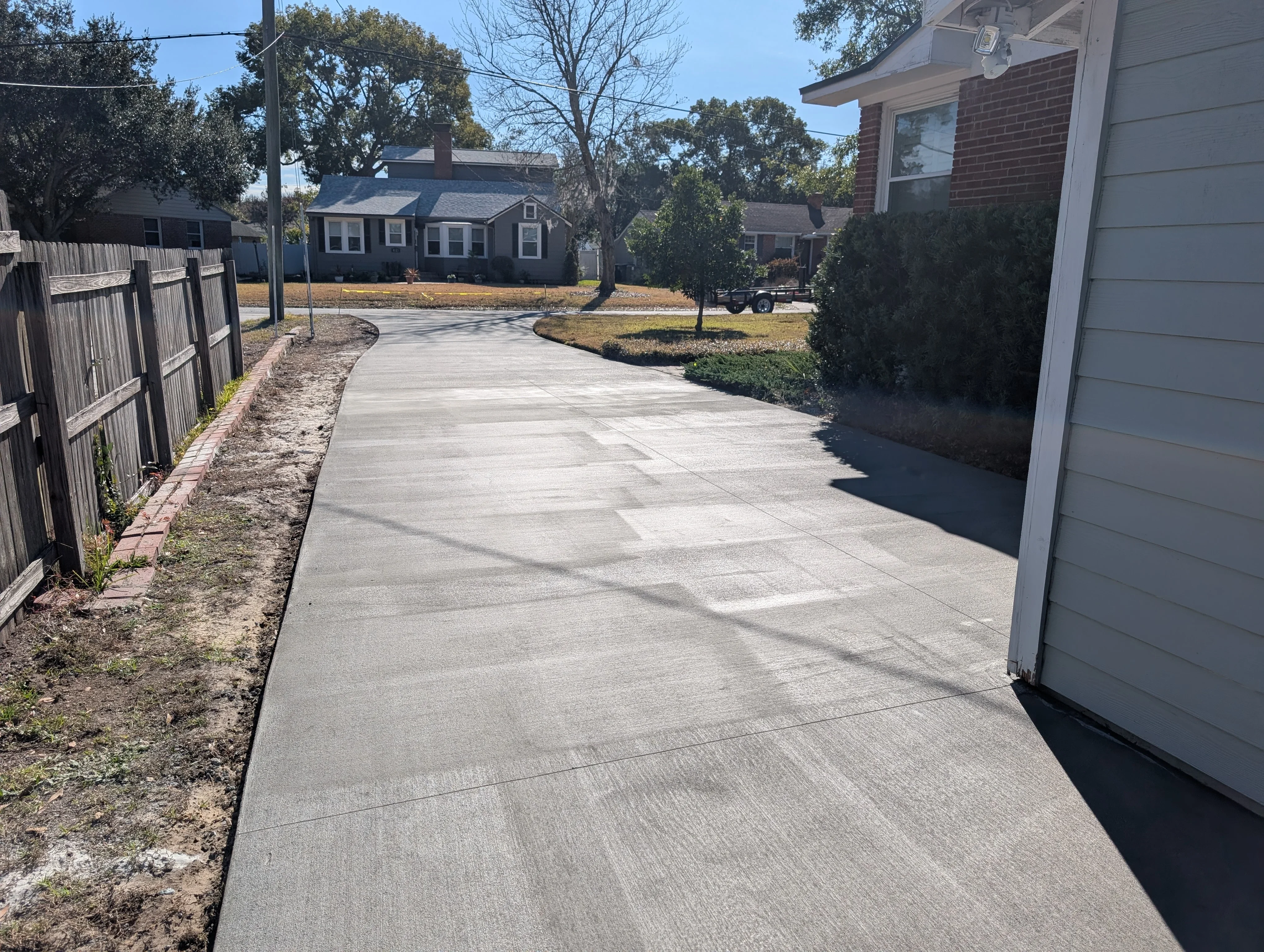 Newly poured concrete driveway with curved layout and control joints, adjacent to garage