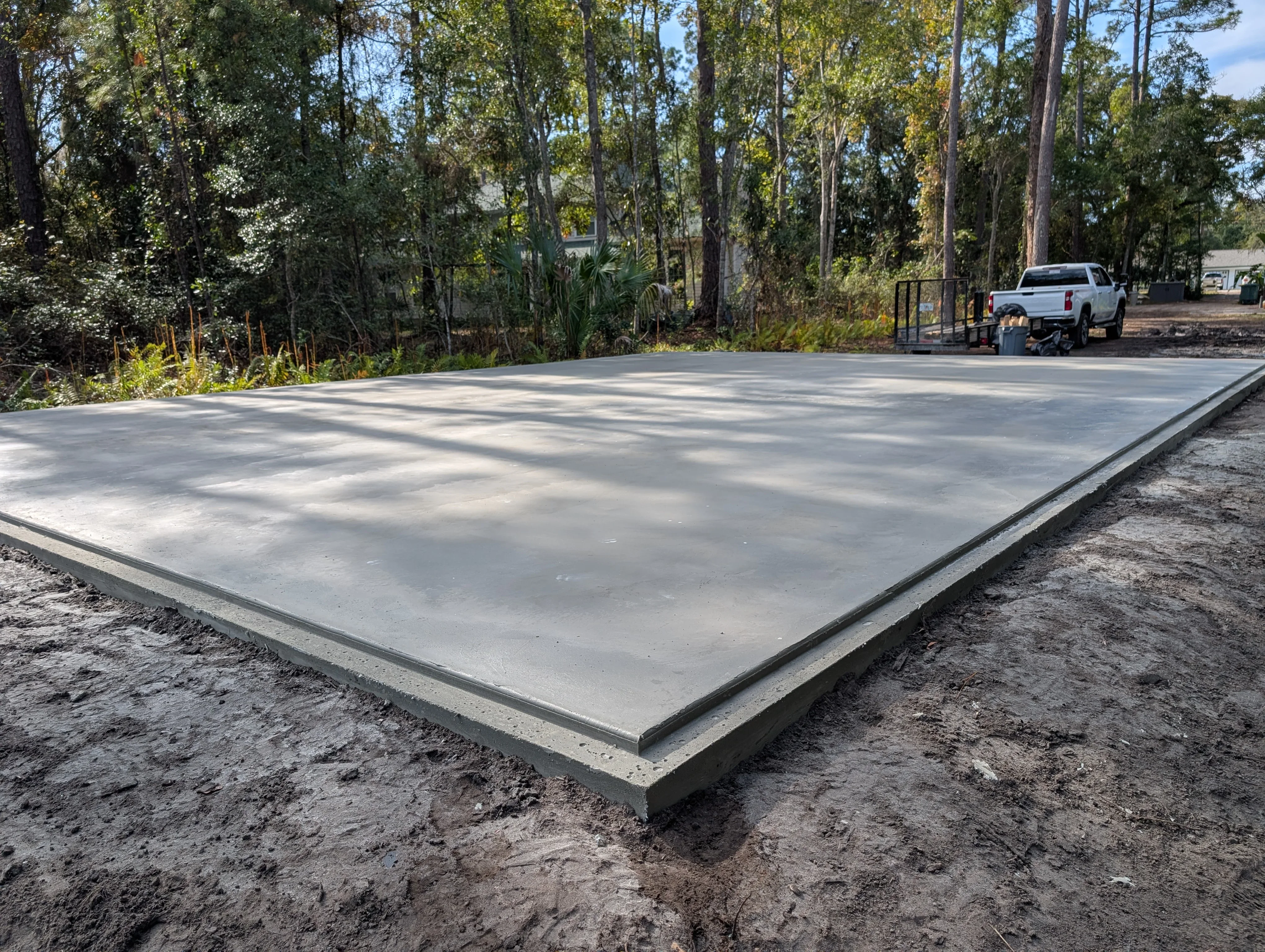 Finished concrete pad with gray concrete surface and defined edges on prepared ground