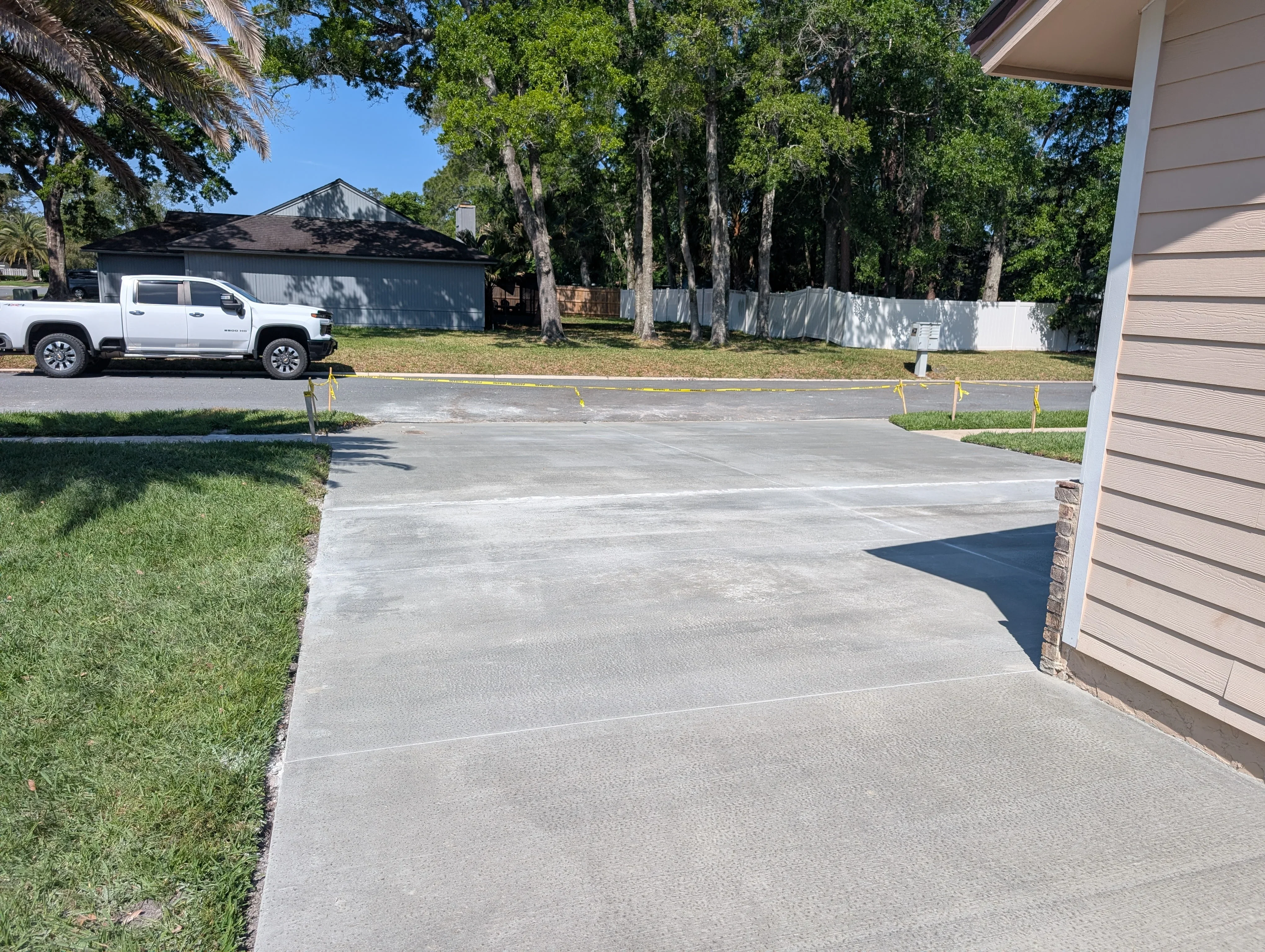 New concrete driveway with control joints, residential garage and landscaping visible