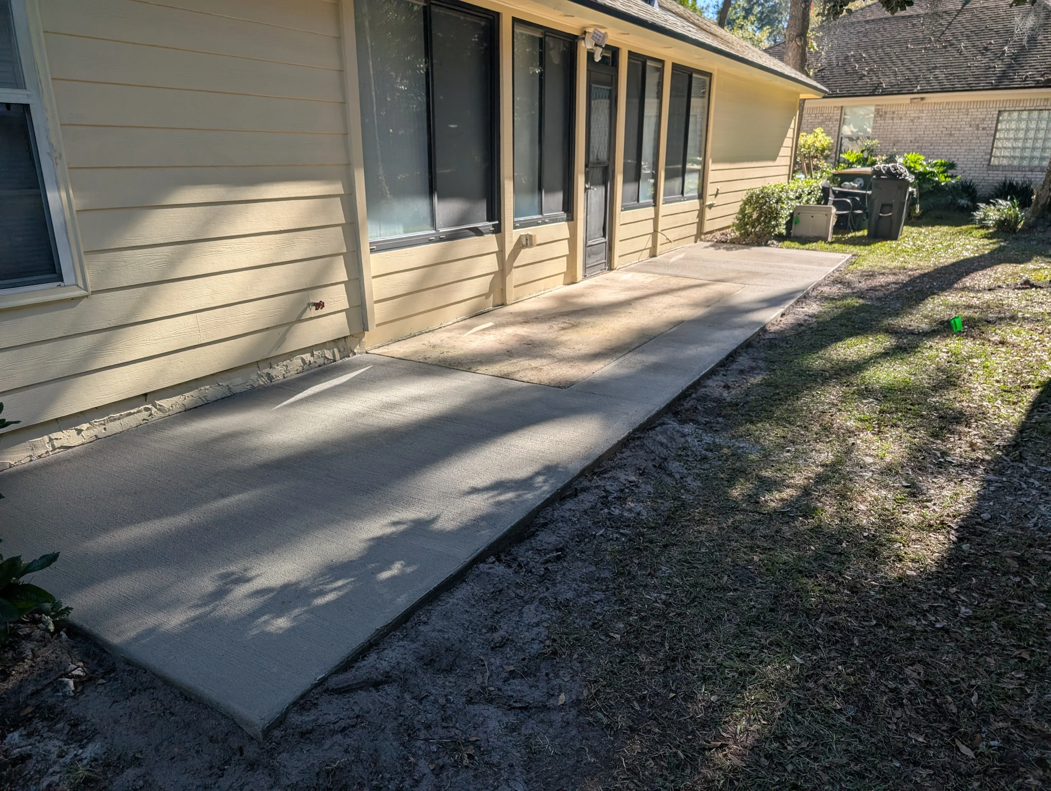 Finished concrete patio and walkway with clean edges next to residential home