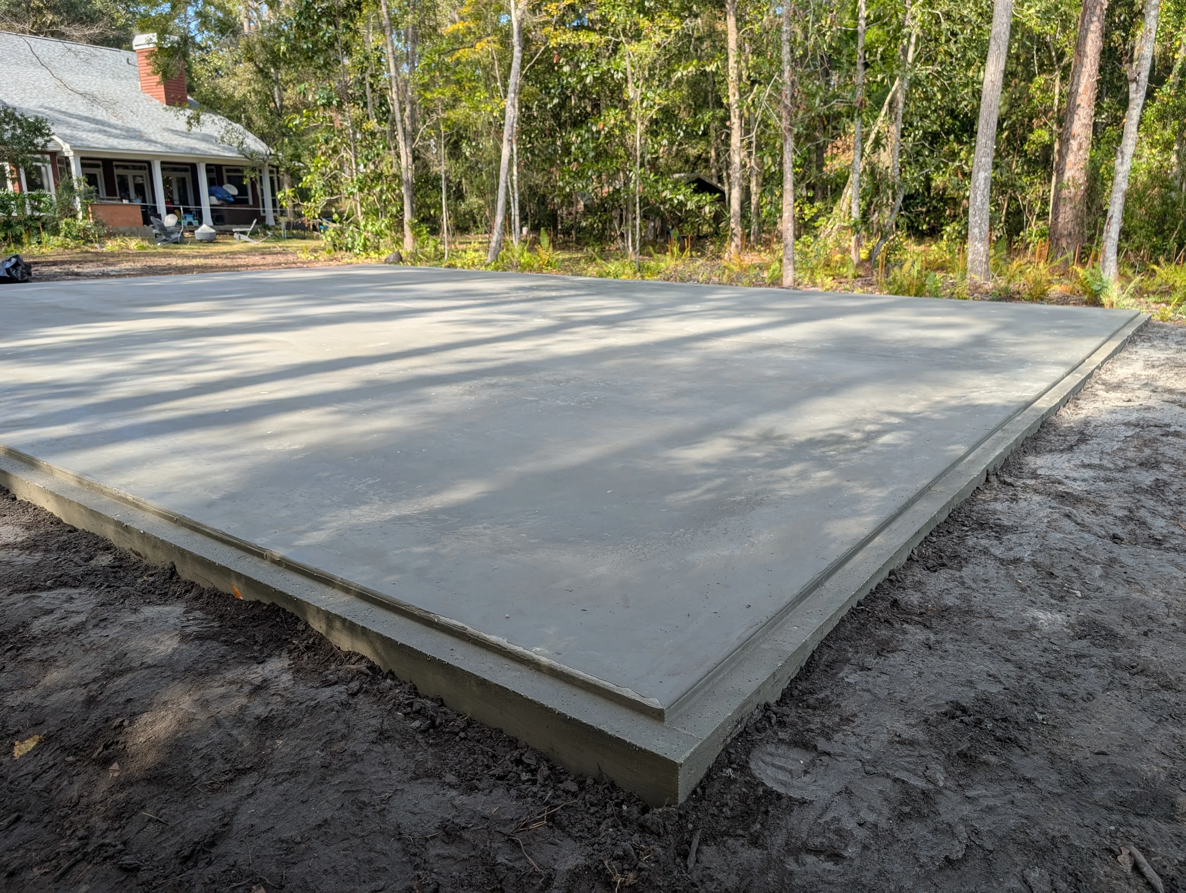 Finished concrete pad with control joints and concrete foundation border on prepared base