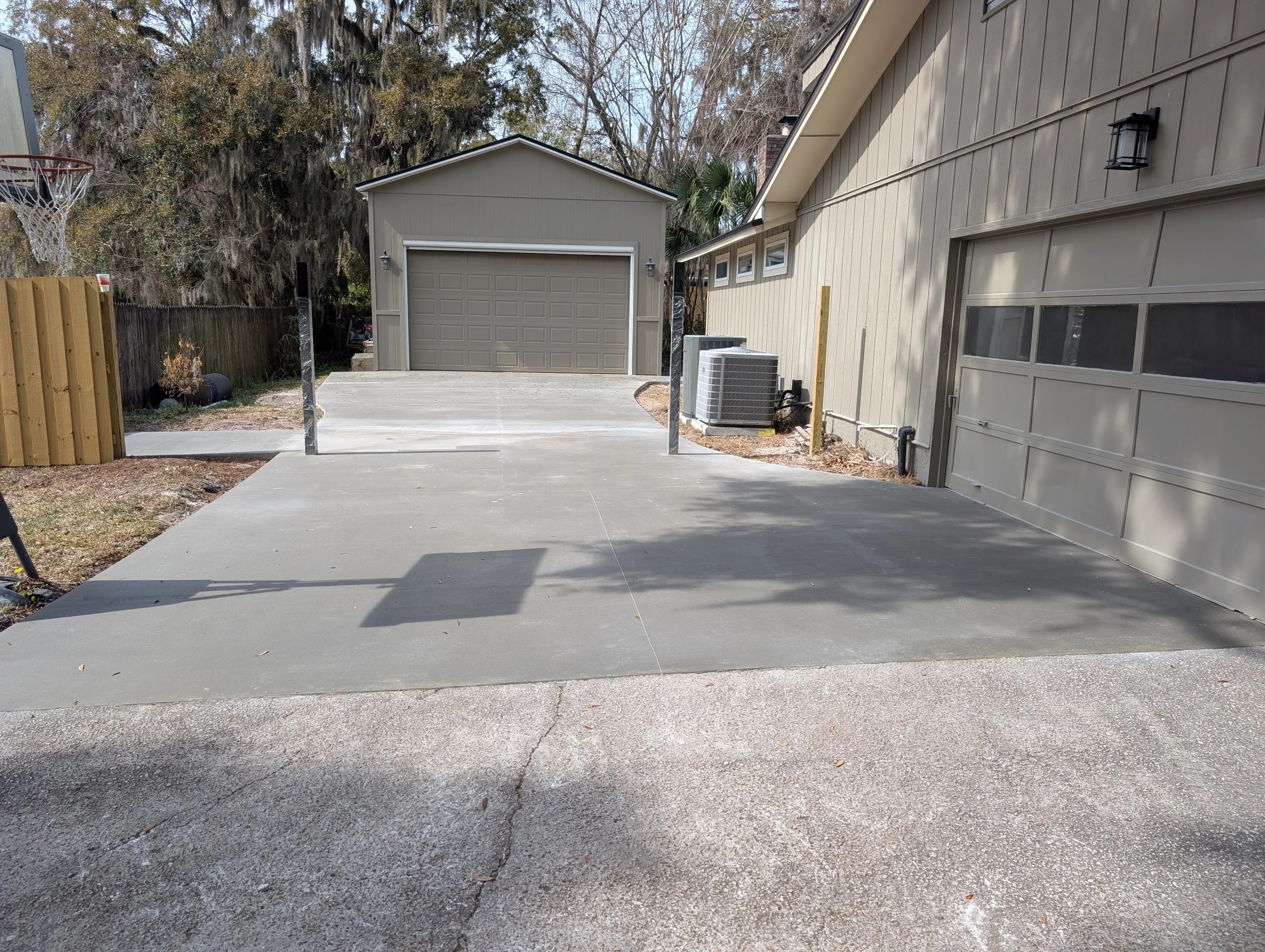 New gray concrete driveway extension with control joints leading to residential garage
