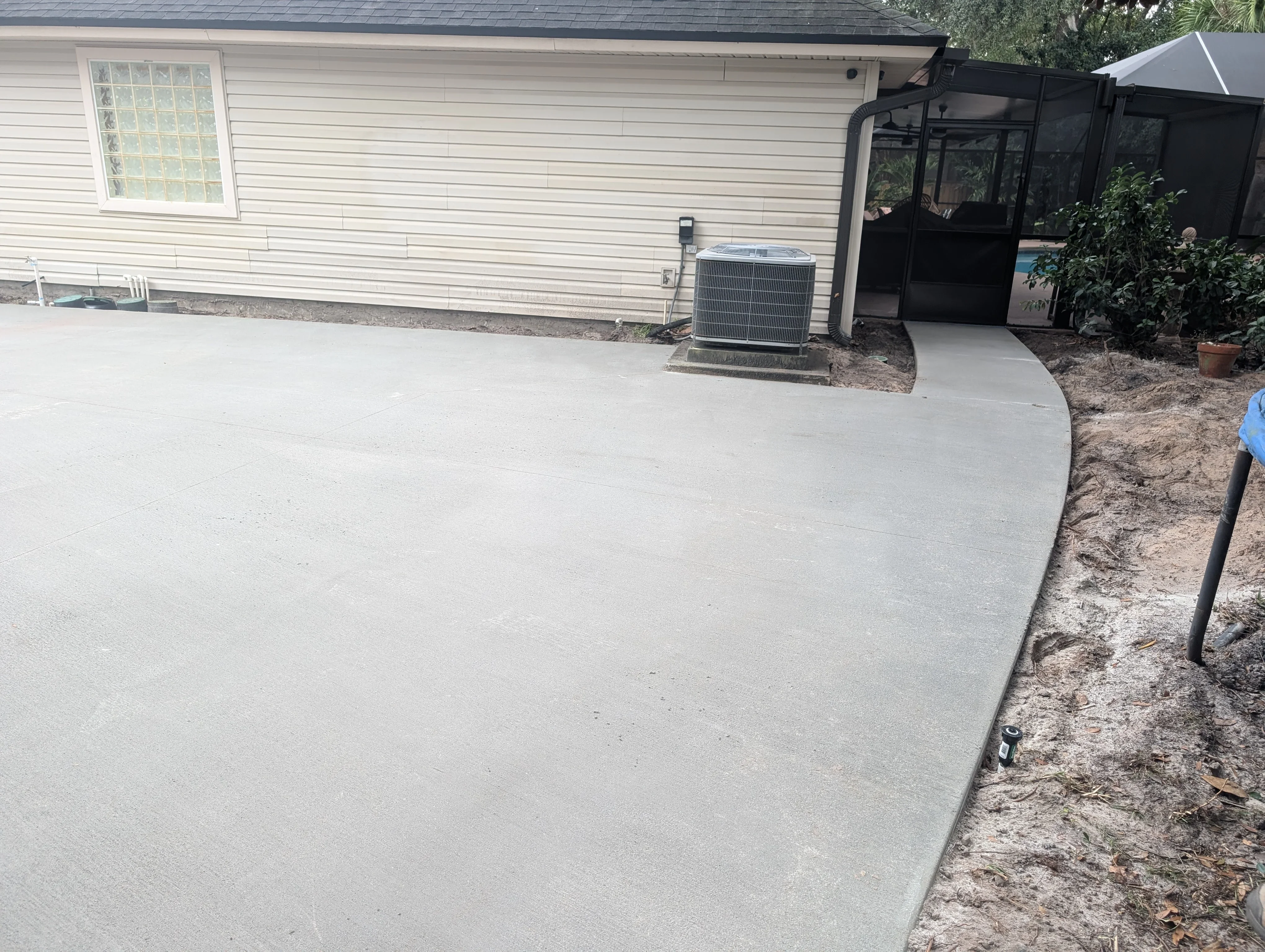 Newly poured concrete patio with smooth finish and defined edges next to residential home