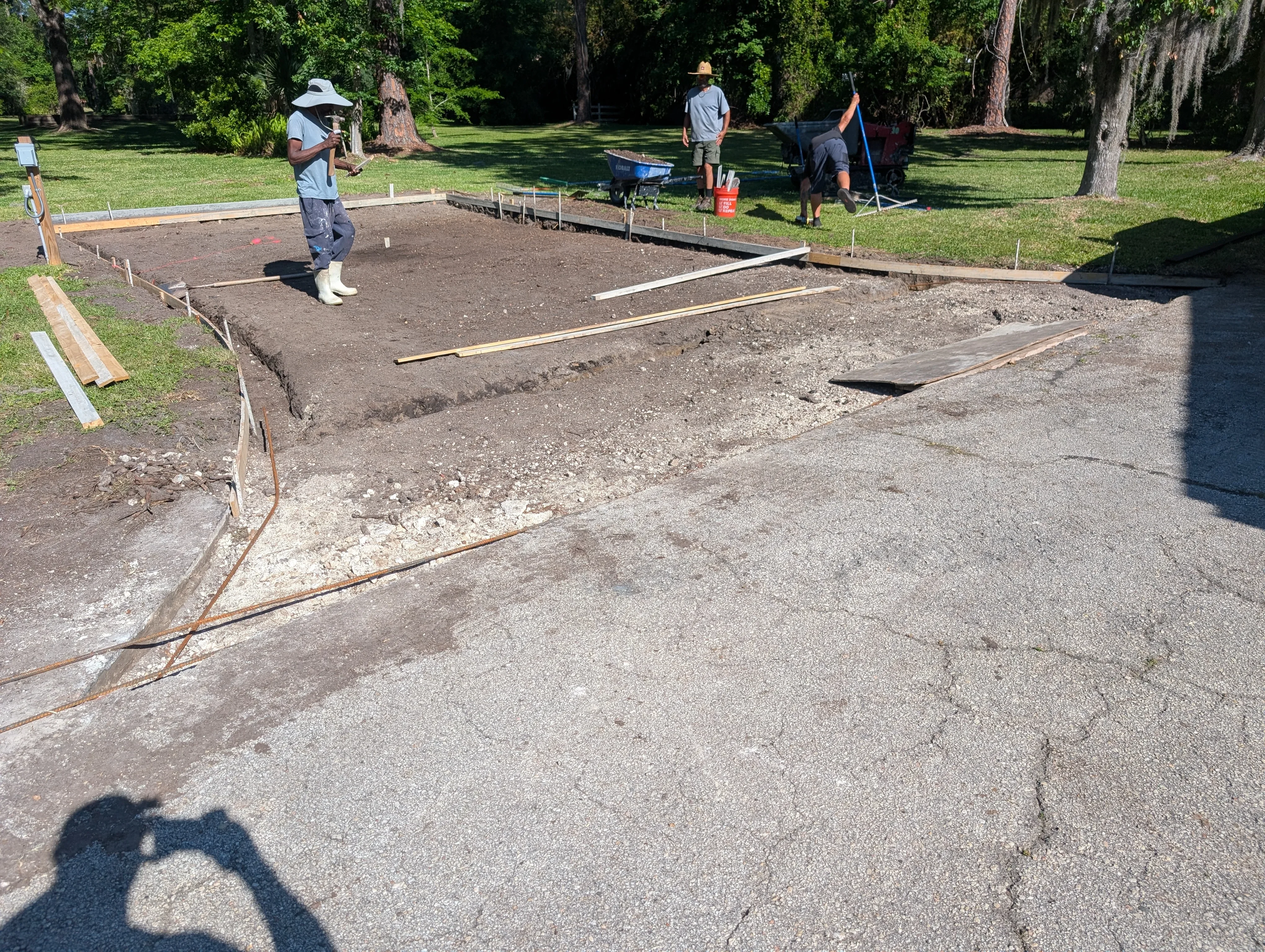 Concrete pad site with excavation, wooden forms, and gravel subbase preparation