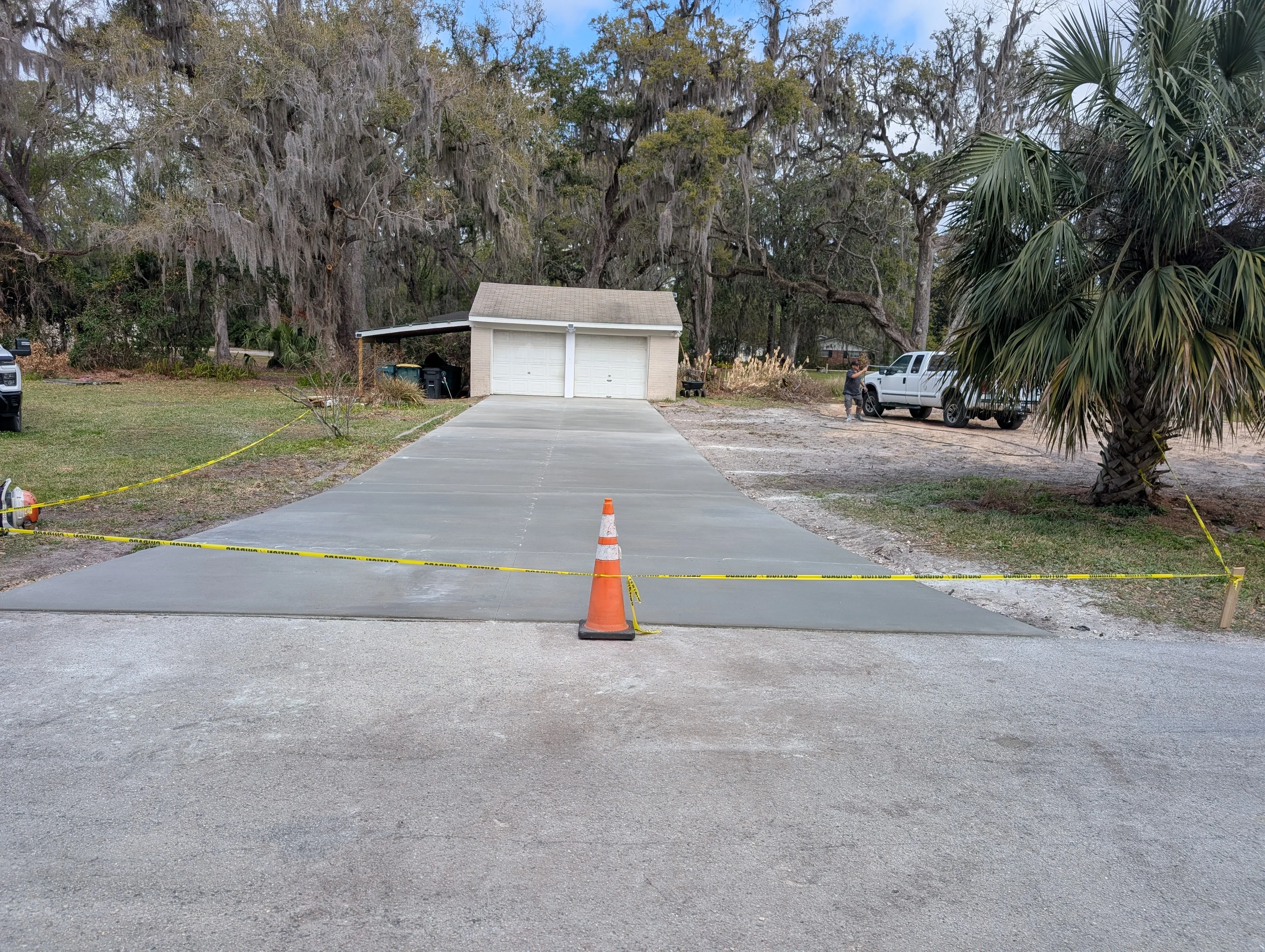 Newly poured concrete driveway with two-car garage, traffic cones marking wet concrete