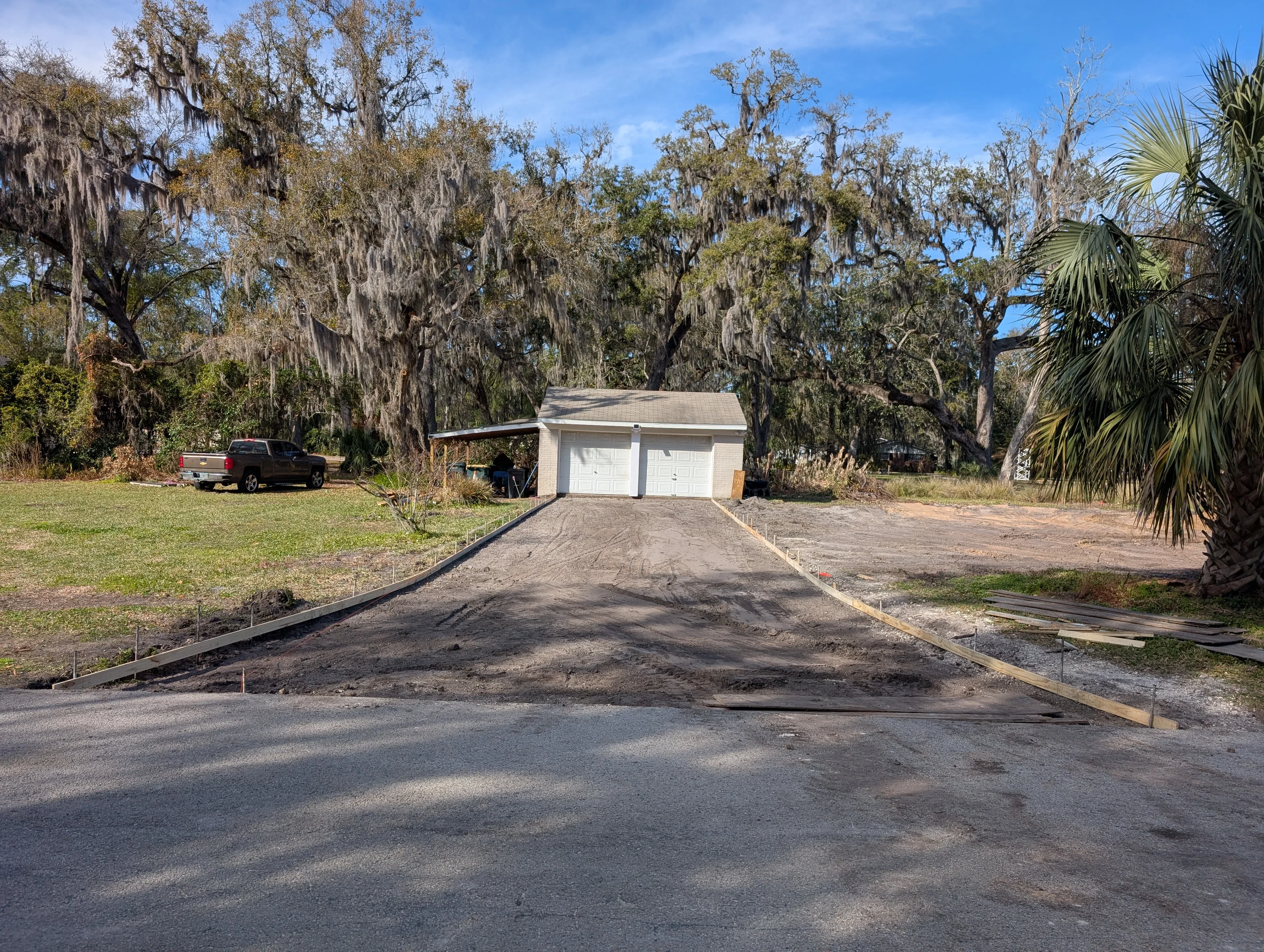 New concrete driveway with wooden edge forms leading to white two-car garage